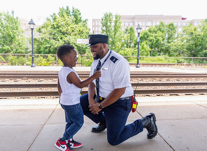 Amtrak staff bending down to talk to little boy